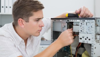 Young technician working on broken computer in his office